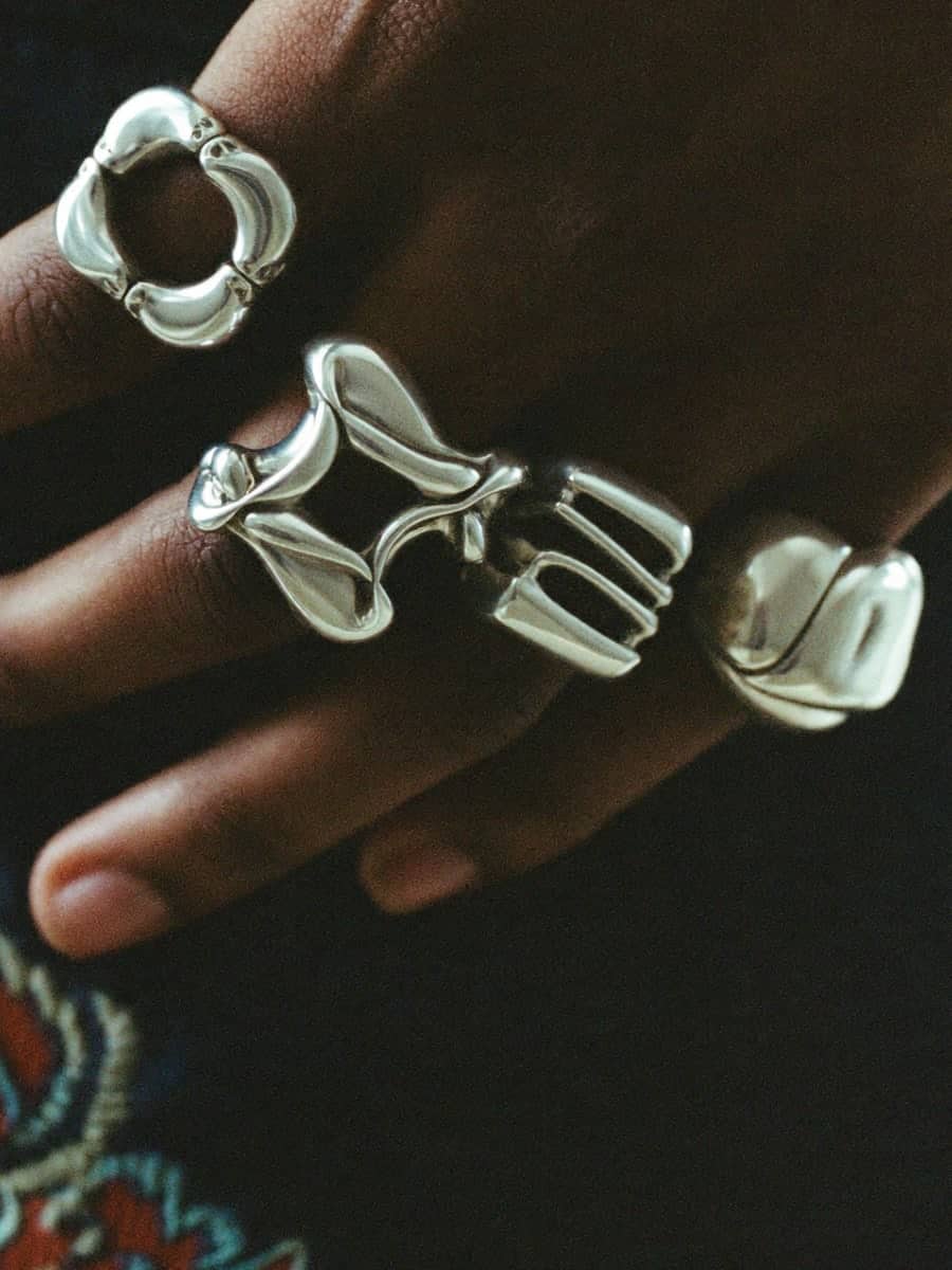 Three molten-looking silver rings on a hand
