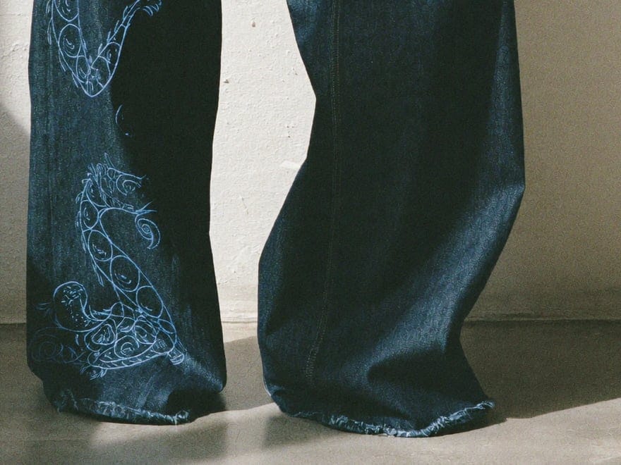 The dragon's tail curling into the raw, pooled hem