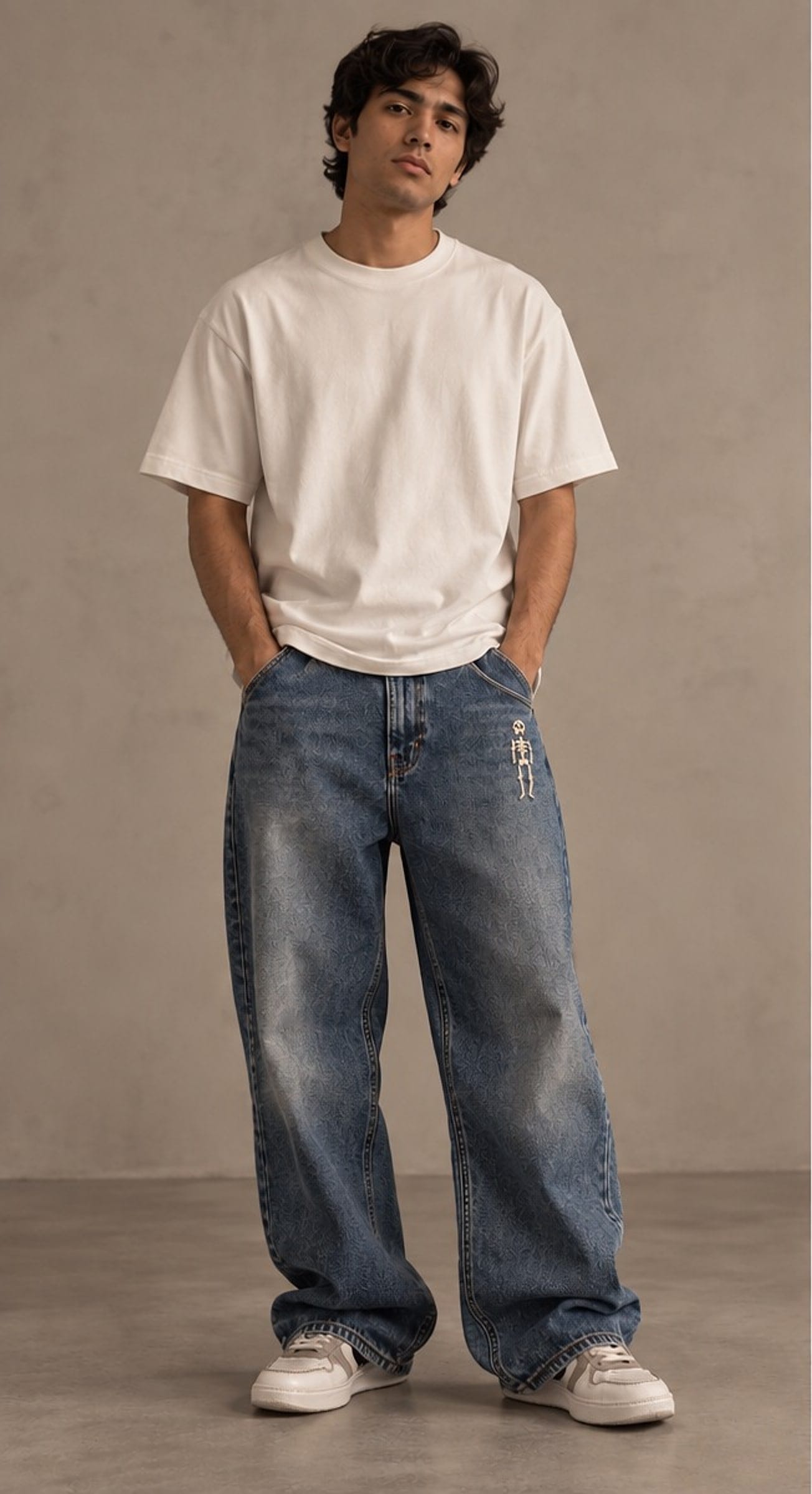 Model in a white tee and vintage-wash wide jeans, hands in pockets, a tiny skeleton below the front pocket